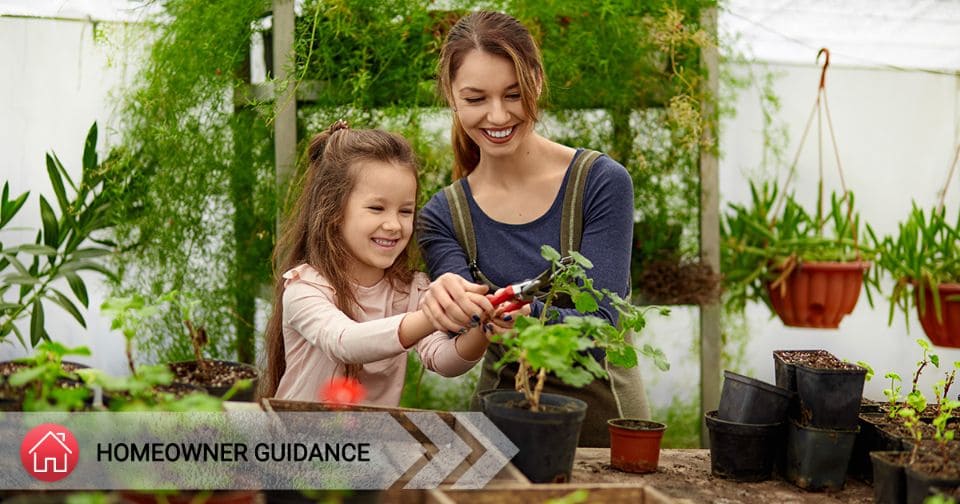 Mother and daughter gardening in a greenhouse.